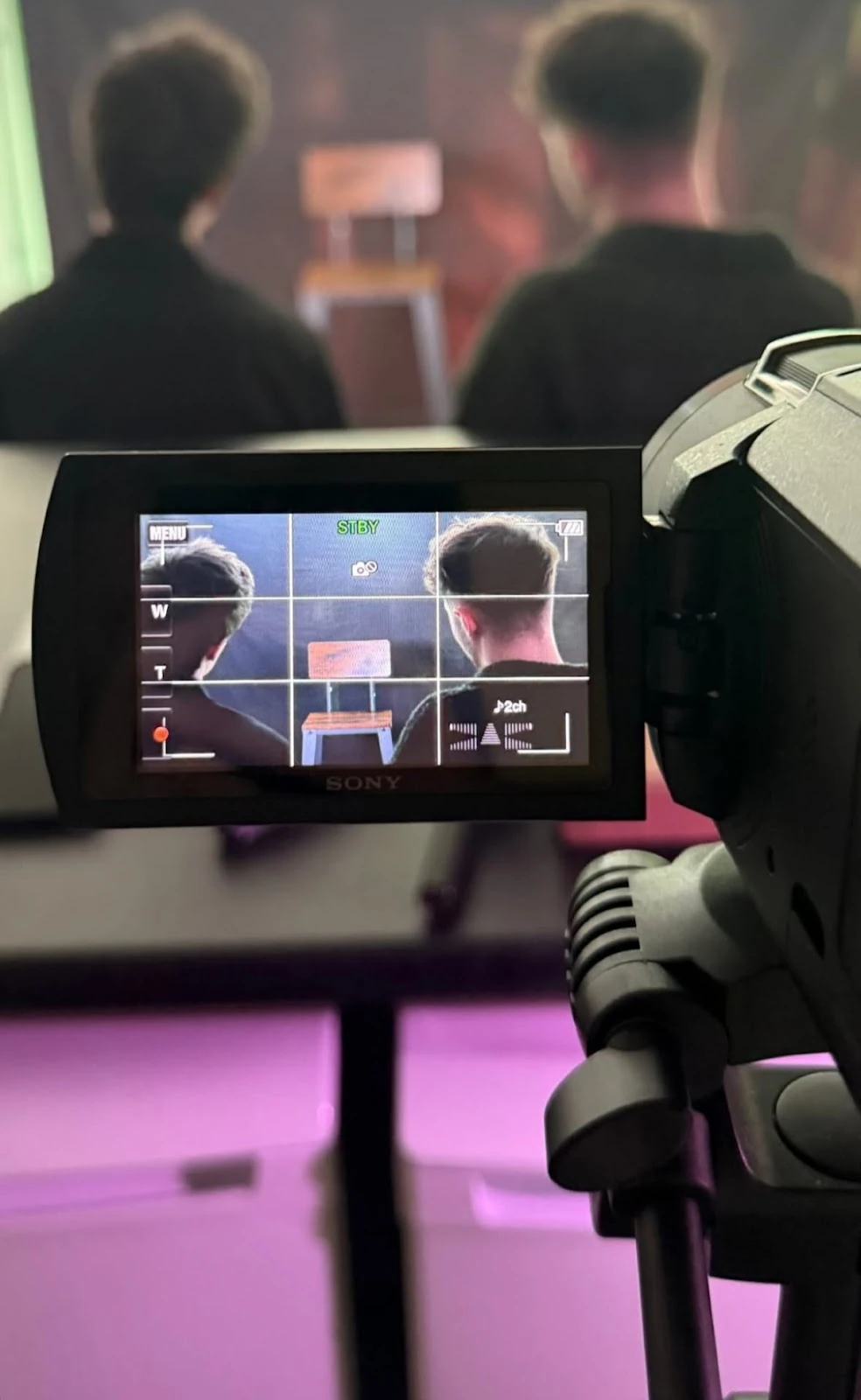 Video camera framing two people from behind.